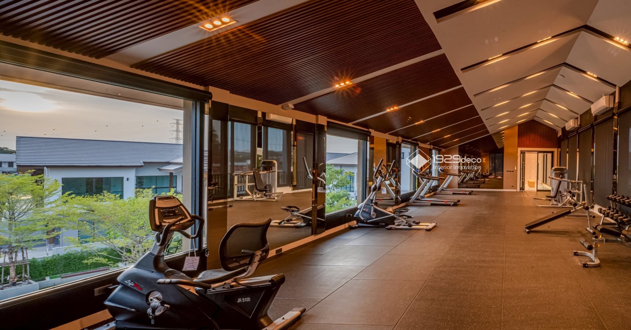 ห้องฟิตเนสพร้อมกระจกและหน้าต่างบานใหญ่ในสโมสร Trinity Ville